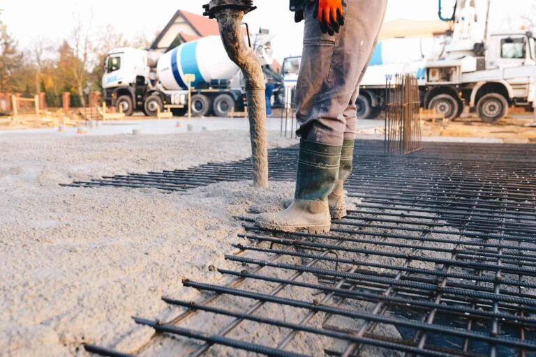 Man building a concrete foundations in Fort Wayne, with a concrete pouring truck in the background. commercial concrete services in woodburn. Best commercial concrete contractor in Leo-Cedarville