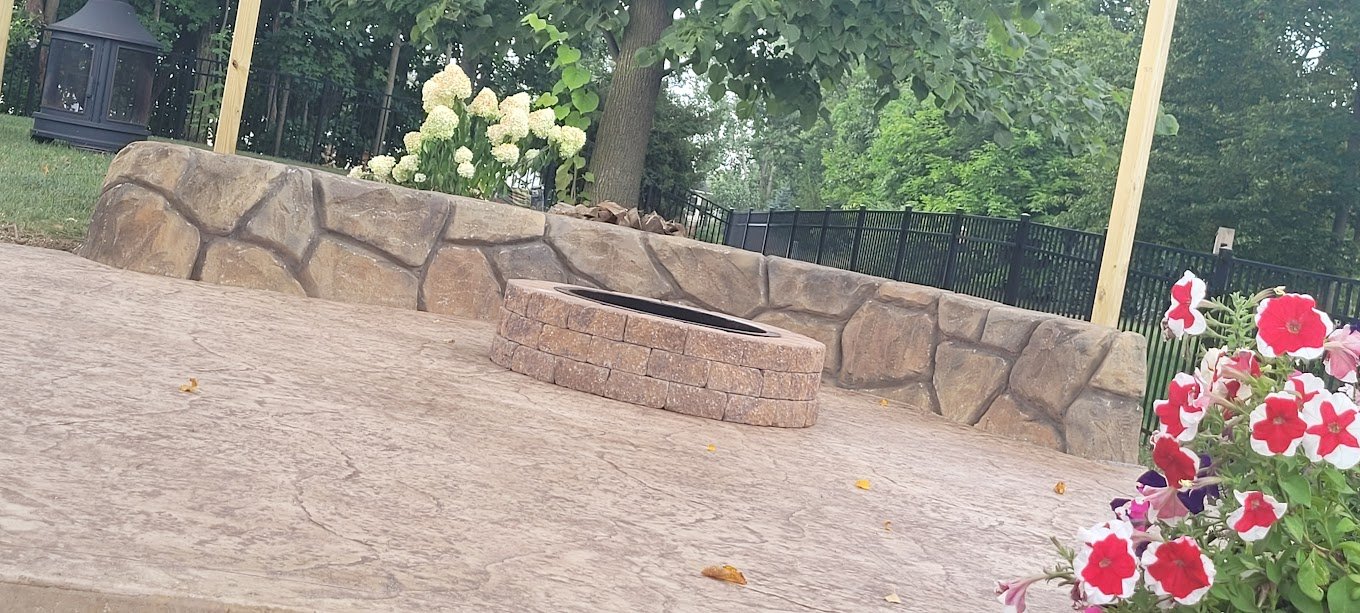 Concrete patio with a retaining wall around it, and a fireplace in the center. Showinng off Crystal Creek's work. The best concrete contractor in Ligonier, IN. The best retaining walls in South Whitley