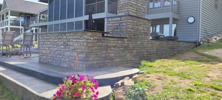 Large custom retaining wall with pink flowers infront of it. Showing off Crystal Creek - The best concrete contractor in Bluffton, IN.