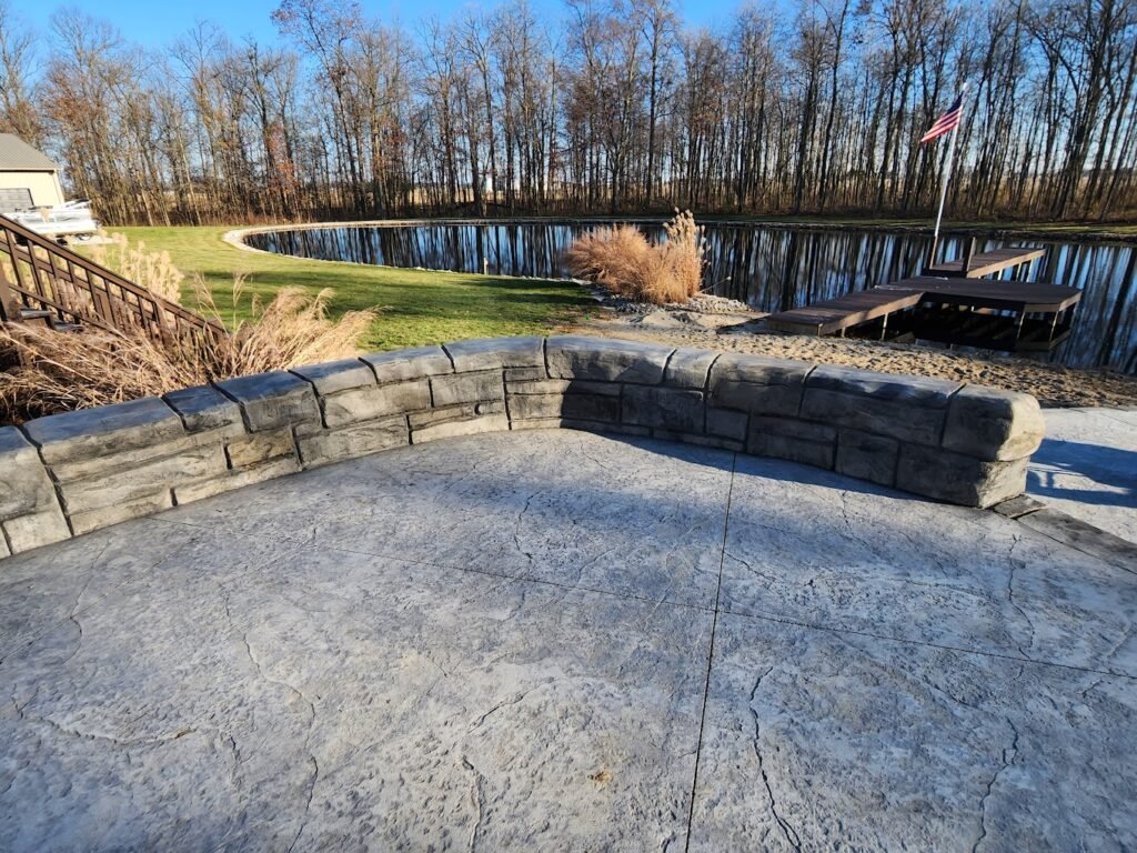 Concrete stamped patio with a retaining wall around it, overlooking a pond. Showing off Crystal Creek - the top concrete contractor in Huntington, IN. Concrete patios in Grabill. Retaining walls in Leo-Cedarville. Retaining walls in Roanoke