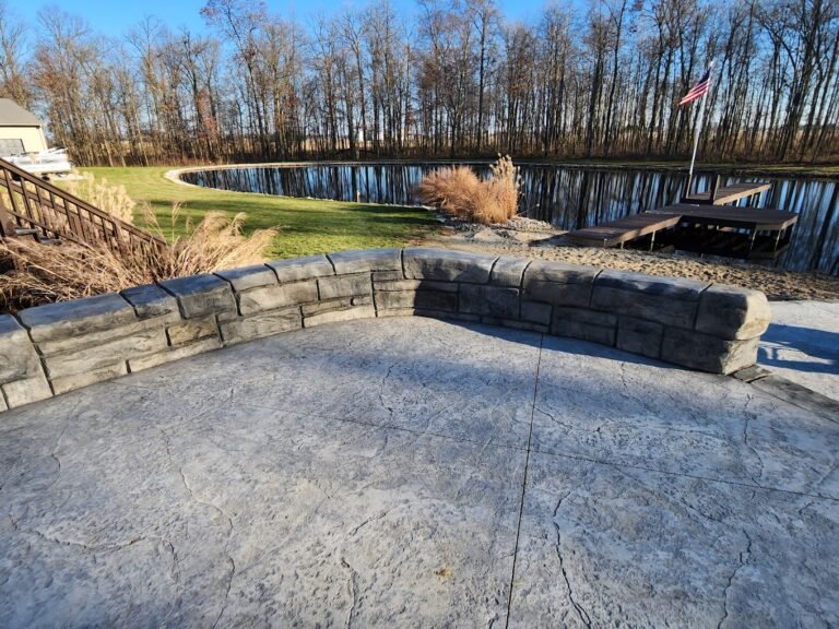 Concrete stamped patio with a retaining wall around it, overlooking a pond. Showing off Crystal Creek - the top concrete contractor in Huntington, IN.