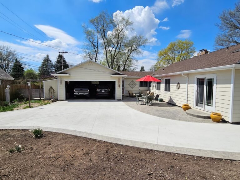 Freshly poured concrete driveway in front of a one-story house