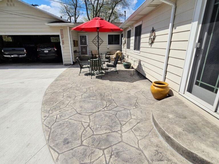 Patio connected to the side of the house and the driveway, with a red umbrella opened. Showing off the best concrete contractor in Churubusco, IN