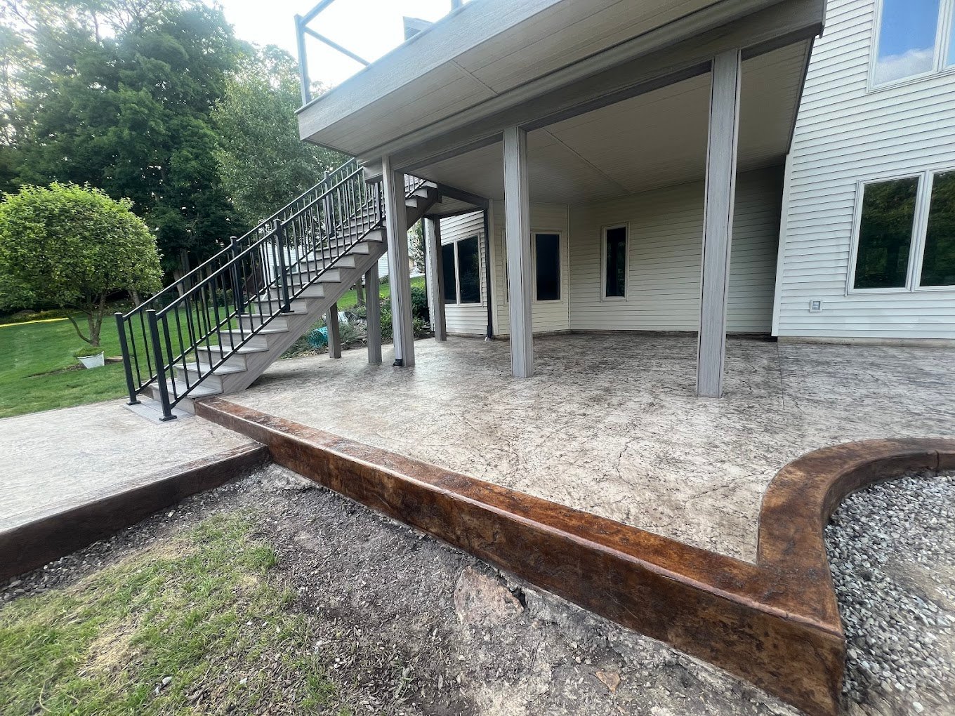 Stamped patio with a brown border. Stairwell leading up to a deck. Showcasing Crystal Creek - the top concrete contractor in Van Wert County. Concrete patios in Decatur. concrete patios in Avilla