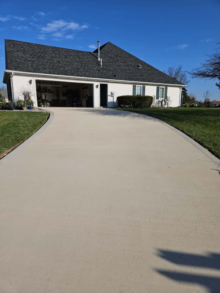 Smooth and durable concrete driveway leading to a suburban home in Fort Wayne, surrounded by a well-kept yard. Driveway replacement in Leo-Cedarville