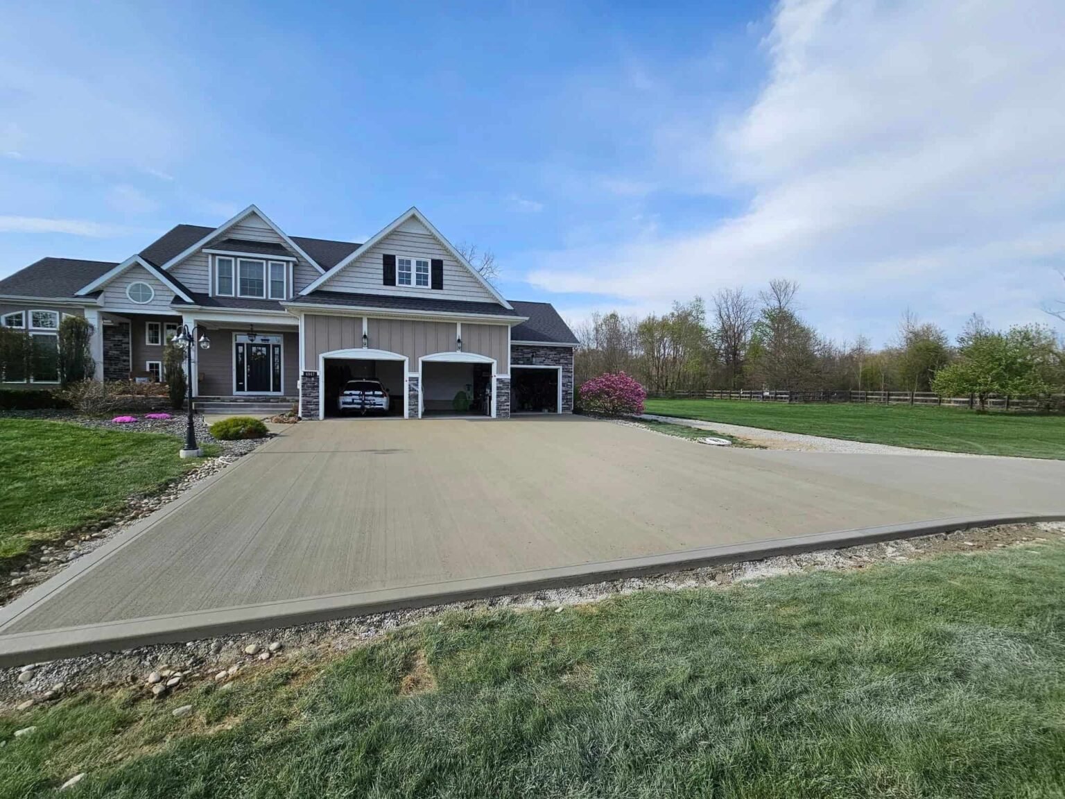 Modern suburban home in Fort Wayne featuring a newly installed concrete driveway and a beautifully landscaped yard.