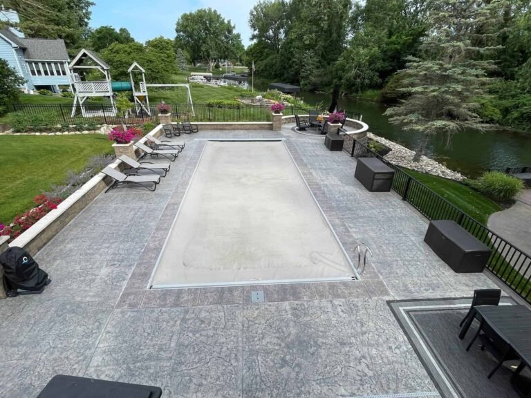 Stamped concrete pool deck with a natural stone finish, surrounded by landscaping and a scenic backyard in Columbia City, Indiana 46704.