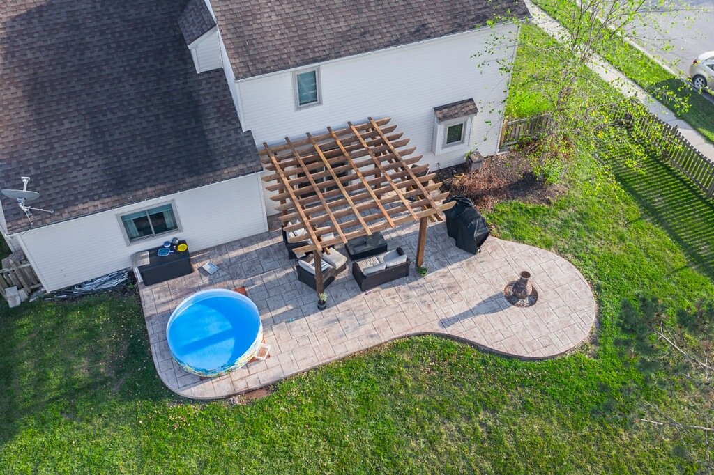 Drone Shot of a white home with a patio and pool, done by the best concrete contractor in South Whitley, IN - Crystal Creek. Concrete patios in Waterloo