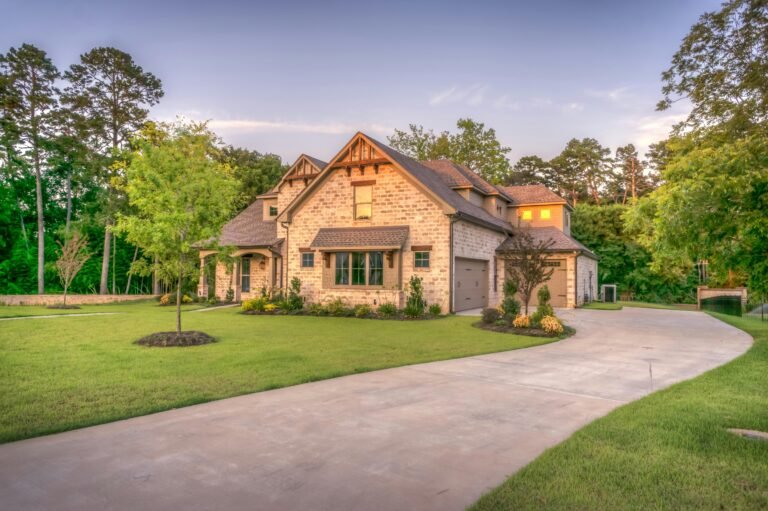 concrete driveway leading to the exterior of a tan house