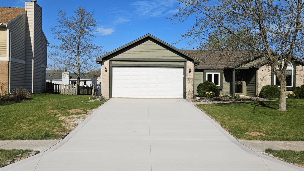 Concrete crew finishing a driveway on a mild spring morning, illustrating the best time to pour concrete in Indiana.
